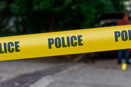 Yellow warning tape with the words Police on a blurred background of the crime scene. Crime news template with copy space for textの写真素材