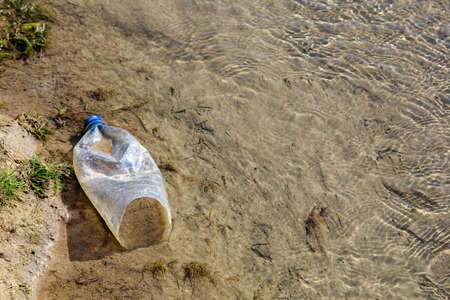 Bottles discarded in nature. Environmental pollution with plastic waste. Hazardous and toxic waste. Ecological disaster of the planet. Causes of climate change. Background with copy space for textの写真素材