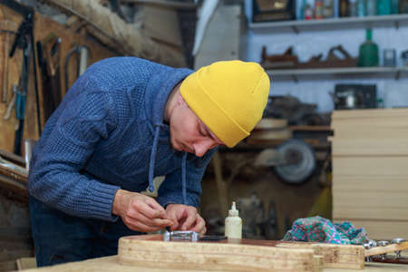 A man in a workshop works with a wooden product. Selective focus backgroundの写真素材
