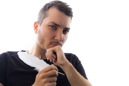 Handsome young man with quill pen, selective focus on eyes. Portrait on a white background.の写真素材