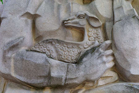 A lamb in the hands of a villager, an element of a monument of an important Christian symbol. Background with copy space for text or inscriptions.の写真素材