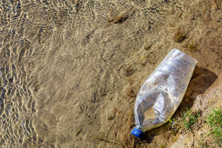 Bottles discarded in nature. Environmental pollution with plastic waste. Hazardous and toxic waste. Ecological disaster of the planet. Causes of climate change. Background with copy space for textの写真素材