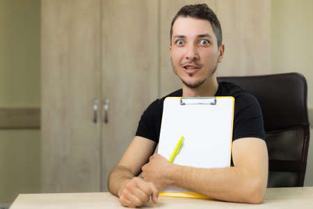 Young handsome man or adult guy in the process of work on a blurred background of the office.