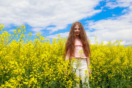 Smiling teenage child. Girl in nature, lifestyle. Cheerful lightning yellow color of blooming...