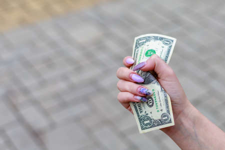 1 dollar in a female hand, selective focus. Background with copy space for text or inscriptions.の写真素材