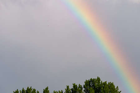 Rainbow in the cloudy sky during the rain. Background with copy space for text