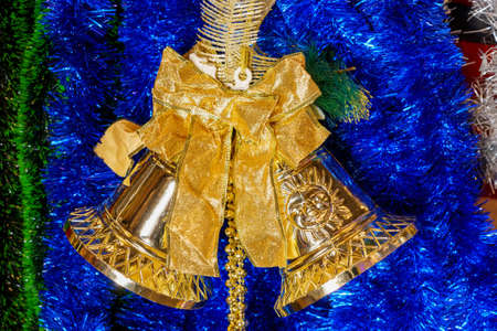 Gold bells and blue tinsel as a symbol. Christmas decor for the interior on a store shelf. Winter symbol, New Years atmosphere. Background with copy space for textの写真素材