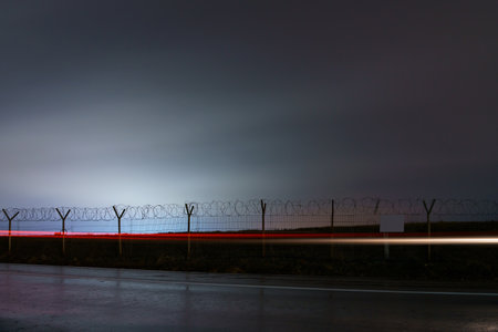 Protected area fence with barbed wire in the dark of night. Background with copy space for text