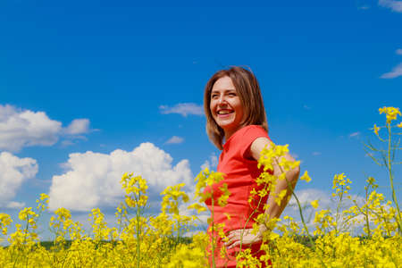 Young pretty woman in colored dress on lightning cheerful yellow background of blooming rapeseed field. Freedom conceptの写真素材