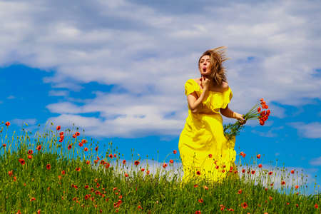 A woman in a yellow dress shows her tongue in a field in nature. Great mood concept