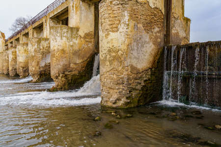 An old abandoned hydroelectric power station on a small river. Apocalyptic background with copy space for text.の写真素材