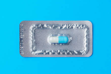 Blister or pack of one very important and expensive tablet or pill. Classic traditional medical blue background. Medicine and pharmacology.の写真素材