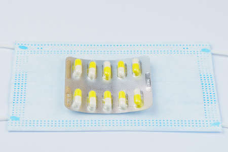 Medical surgical mask and blister or pill pack. White isolated background. The concept of treatment of coronavirus infection covid-19. Selective focus and copy space.の写真素材