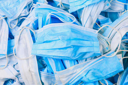 Used disposable medical masks background. Medical waste. Garbage and the environmental impact of the covid-19 coronavirus pandemic. Ecology concept.の写真素材