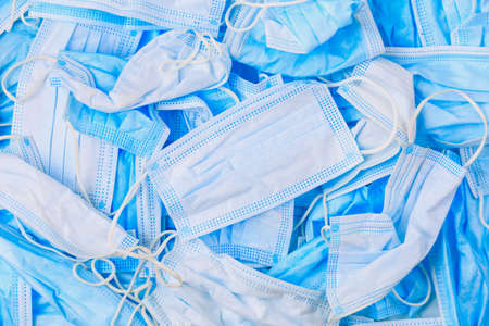 Used disposable medical masks background. Medical waste. Garbage and the environmental impact of the covid-19 coronavirus pandemic. Ecology concept.の写真素材
