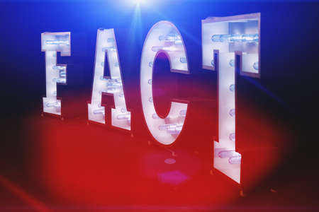 The inscription FACT made with light bulbs with selective focus and highlights, toned. Background with copy space for text. Conceptual backdropの写真素材