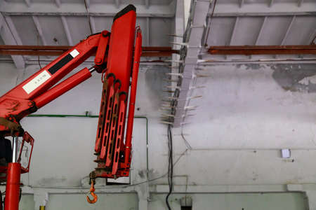 Boom of folding crane on blurred background of factory building or industrial area with copy space...
