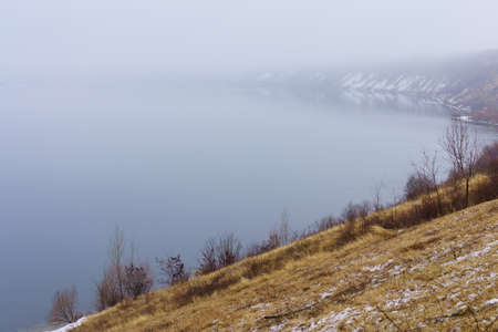 Foggy bank of a river or reservoir in damp cold weather. Background with copy space for textの写真素材