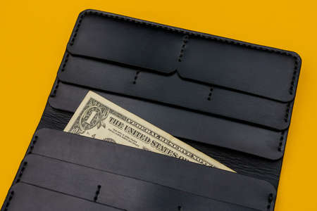 Corner of a cash 1 dollar bill with a leather wallet in the background. Selective focus, copy space for textの写真素材