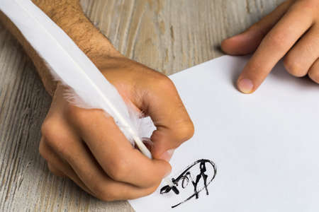 Male hand with a goose feather. Poetry and journalism symbol. The concept of writing texts....