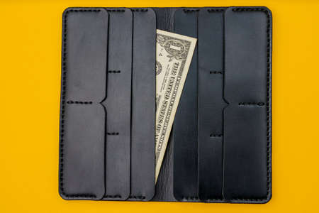 Corner of a cash 1 dollar bill with a leather wallet in the background. Selective focus, copy space...