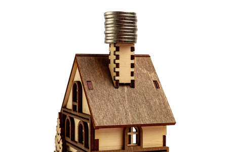 The roof of a wooden toy house with coins on the chimney. The concept of heating and energy costs, toned. White isolated backgroundの写真素材