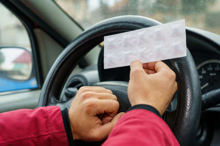 Pack of pills in the hands of the driver on a blurred background of the steering wheel in the car....