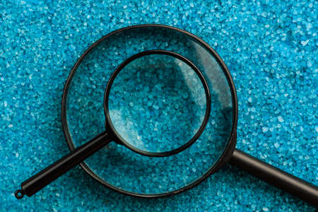Two magnifiers of different sizes on the background of sea aromatic bath salts. Concept of searching for romantic pleasure. Abstract copy spaceの写真素材