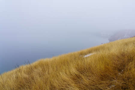 Foggy bank of a river or reservoir in damp cold weather. Background with copy space for textの写真素材