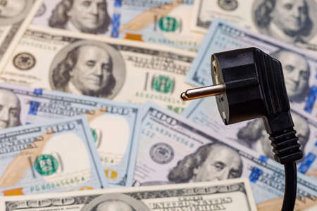 Electric cord plug and dollars on a blurred background, selective focus. The concept of the energy crisis and electricity inflation. Rising electricity prices. Copy space.の写真素材