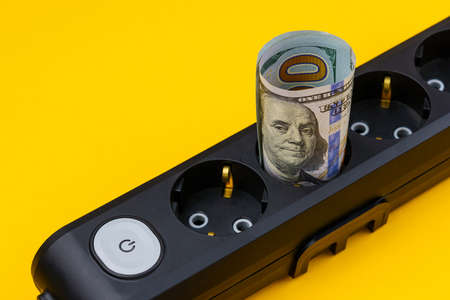 Rolled dollar bills in power strip sockets. The concept of the energy crisis and electricity inflation. Rising electricity prices. Copy space for text.の写真素材