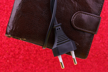 An electrical wire tied into a knot on an old decrepit wallet. The concept of the energy crisis and...