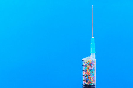 A classic disposable syringe filled with symbolic hearts. Love concept. Background with copy space for text. Blue medical backdrop.の写真素材