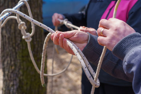 Hands of a tourist tying knots on a rope with selective focus. Background with copy space for textの写真素材