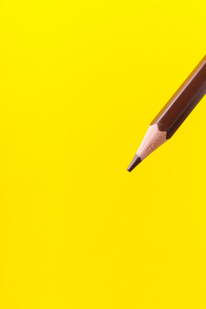 Colored pencil close-up with selective focus on the stylus and a blurred yellow background. Copy space for text.の写真素材