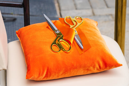 Golden scissors on a red pillow with selective focus and a blurred background. Startup and business grand opening concept.の写真素材