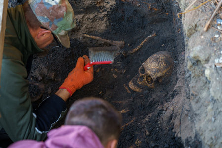 October 23, 2021 Balti Moldova archaeological excavations. Team of archaeologists in the pit in the process of work. Human skull in the ground.のeditorial素材