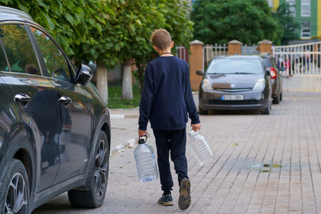 A teenager with plastic bottles goes for water. The problem of lack of water for the citizens. For editorial use. September 24, 2022 Balti Moldova.のeditorial素材