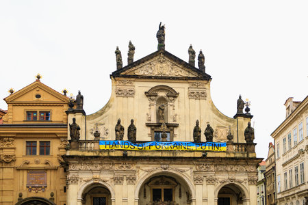 The inscription Hands off Ukraine, Putin. Text on a banner in the colors of the Ukrainian flag on a historic building in a tourist destination. August 24, 2022 Prague Czech Republic.のeditorial素材