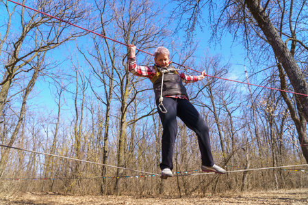 March 27, 2022 Mindrestii Moldova. Tourists amateurs train in the forest to walk on a rope. News editorial backgroundのeditorial素材