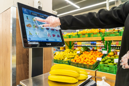 A woman weighs bananas on a scale in a supermarket. April 13, 2023 Beltsy, Moldova. For illustrative editorial use.のeditorial素材