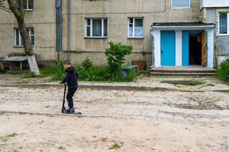 May 16, 2023 Beltsy, Moldova. For illustrative editorial use. A boy rides a scooter on a broken roadのeditorial素材