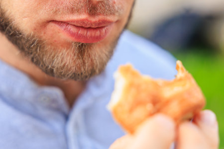 Chewing mouth while eating, man eats mini puff pastry. Background with selective focus and copy spaceの写真素材