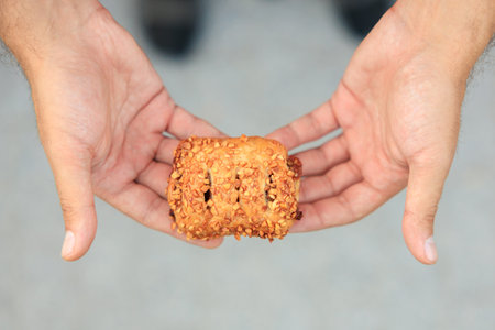 A guy's hand holds a sweet pastry with jam, snack and fast food concept. Selective focus on hands with blurred background and copy space for text.の写真素材