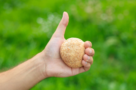 Man's hand holds mini bread, snack and fast food concept. Selective focus on hands with blurred background and copy space for text.の写真素材