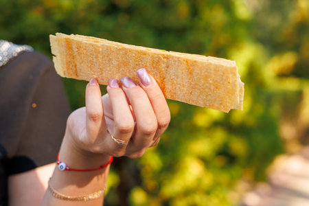 Woman's hand holds long chips, snack and fast food concept. Selective focus on hands with blurred background and copy space for text.の写真素材