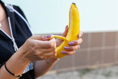 Woman's hand holding bananas, snack and fast food concept. Selective focus on hands with blurred background and copy space for text.の写真素材