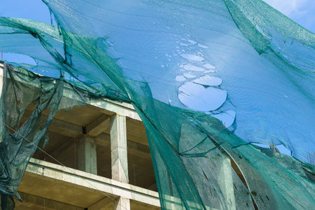 Protective mesh on scaffolding torn by hurricane wind. Background with selective focus and copy...