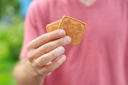 Guy's hand holds cookies, snack and fast food concept. Selective focus on hands with blurred...