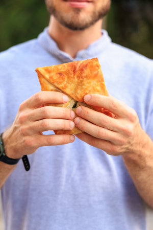 Vertical frame of hands holding pastries, fast food snack concept. Background with selective focus...